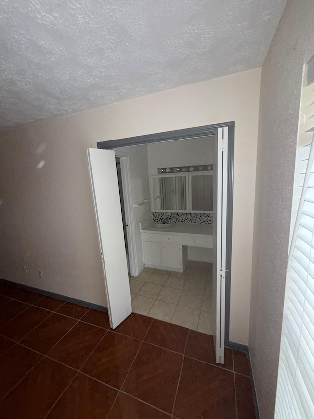 hall featuring a healthy amount of sunlight, dark tile patterned floors, and a textured ceiling