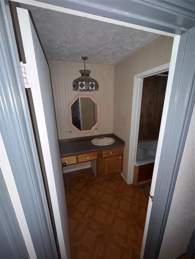 bathroom featuring a textured ceiling, vanity, and parquet floors