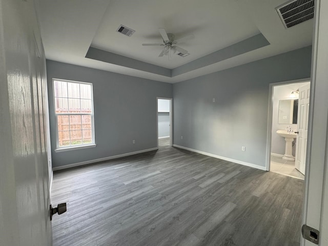 unfurnished room with a tray ceiling, ceiling fan, and dark wood-type flooring