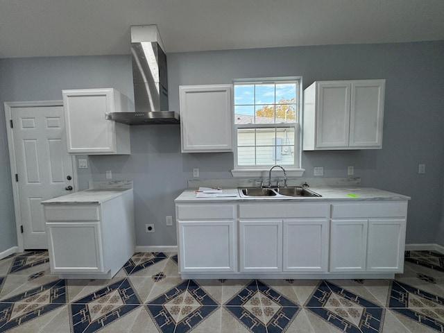 kitchen with sink, white cabinetry, and wall chimney range hood