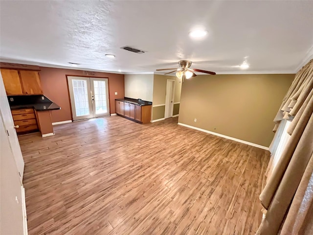 unfurnished living room with french doors, light hardwood / wood-style flooring, ceiling fan, and crown molding