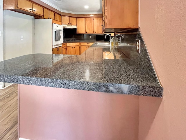 kitchen featuring white appliances, kitchen peninsula, sink, and ornamental molding