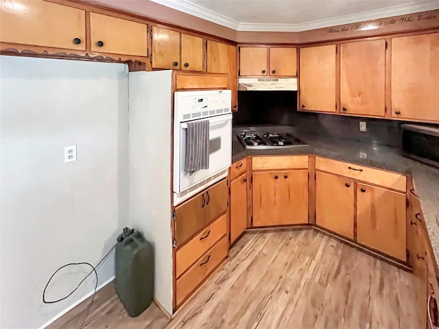 kitchen with stainless steel appliances, crown molding, and light hardwood / wood-style floors