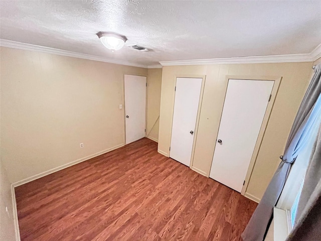 unfurnished bedroom with a textured ceiling, light wood-type flooring, and ornamental molding