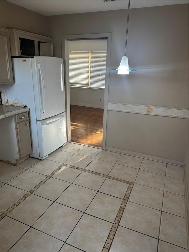 kitchen with light tile patterned flooring, decorative light fixtures, and white refrigerator