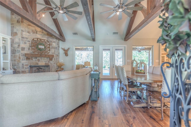 living room with beam ceiling, french doors, a stone fireplace, high vaulted ceiling, and dark hardwood / wood-style floors