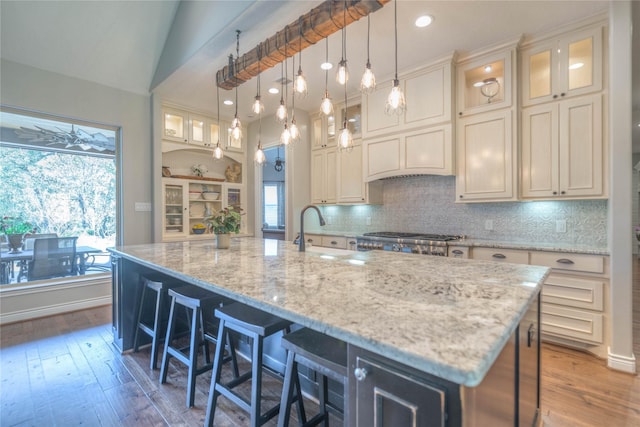 kitchen featuring backsplash, vaulted ceiling, sink, hardwood / wood-style floors, and a large island