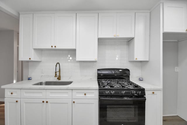 kitchen with gas stove, white cabinetry, sink, and light stone countertops