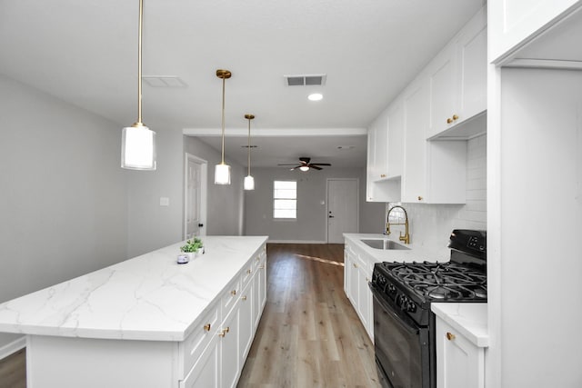 kitchen with gas stove, white cabinetry, and sink