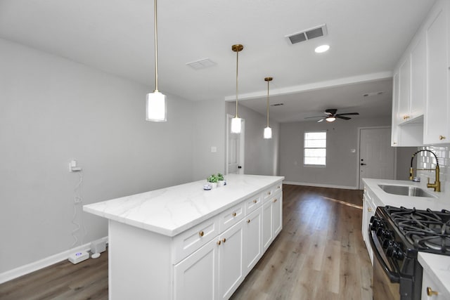 kitchen with a center island, white cabinets, sink, light hardwood / wood-style floors, and light stone counters