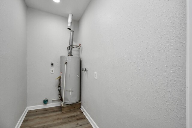 laundry room with electric dryer hookup, dark hardwood / wood-style floors, and gas water heater