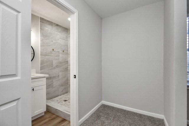 bathroom featuring a tile shower, vanity, and hardwood / wood-style flooring