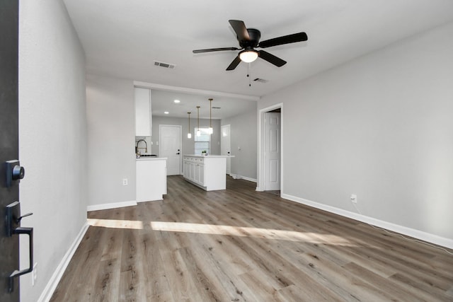 unfurnished living room featuring ceiling fan, light hardwood / wood-style floors, and sink