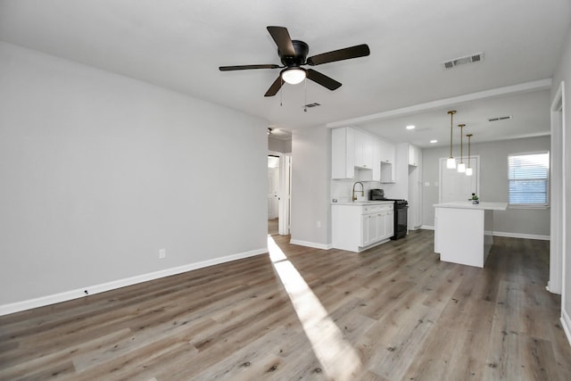 unfurnished living room featuring hardwood / wood-style flooring, ceiling fan, and sink