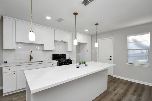 kitchen with dark hardwood / wood-style flooring, black gas stove, white cabinetry, and sink