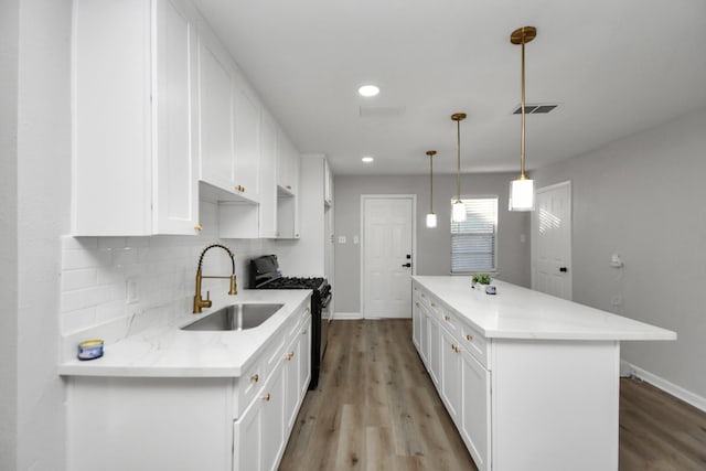 kitchen featuring white cabinetry, sink, black range with gas cooktop, and pendant lighting