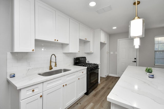 kitchen with gas stove, white cabinetry, and sink