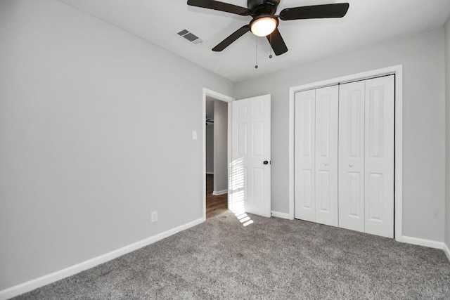 unfurnished bedroom featuring dark colored carpet, a closet, and ceiling fan