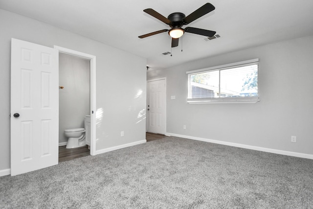 unfurnished bedroom with ensuite bathroom, ceiling fan, and dark colored carpet