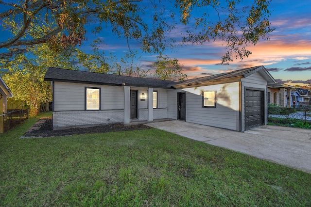 ranch-style home featuring a garage and a lawn