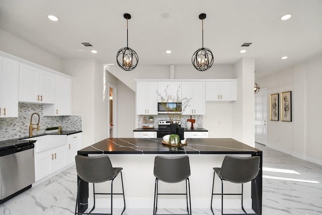 kitchen with decorative backsplash, appliances with stainless steel finishes, a kitchen island, and hanging light fixtures