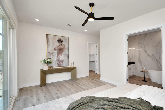 unfurnished bedroom with ceiling fan, light wood-type flooring, a spacious closet, connected bathroom, and a closet