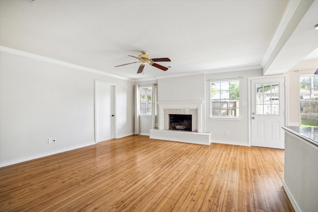 unfurnished living room featuring light wood-type flooring, a wealth of natural light, and ornamental molding