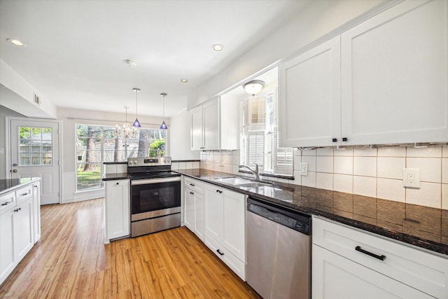 kitchen featuring sink, hanging light fixtures, light hardwood / wood-style flooring, white cabinetry, and stainless steel appliances