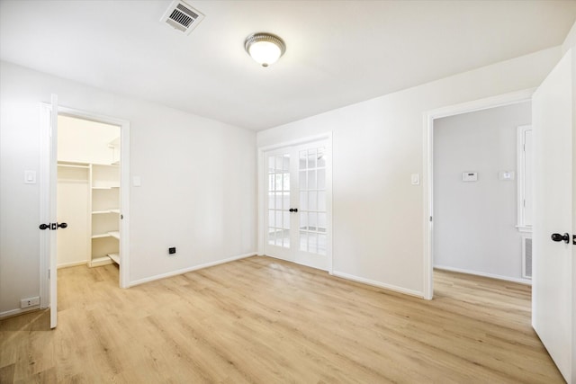 unfurnished room featuring french doors and light wood-type flooring