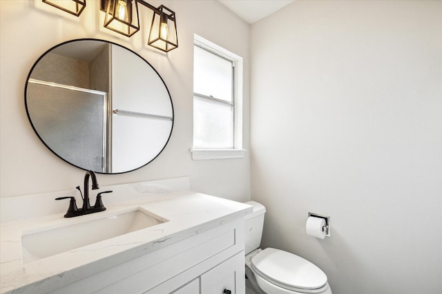 bathroom with a shower with door, vanity, and toilet