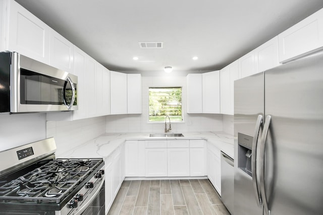 kitchen featuring light stone counters, sink, white cabinets, and appliances with stainless steel finishes