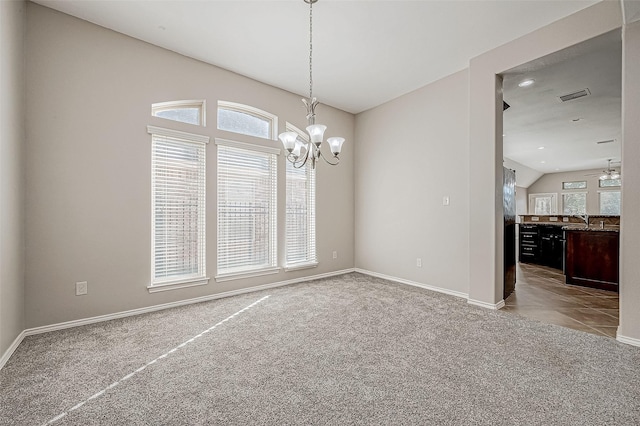 unfurnished dining area with ceiling fan with notable chandelier, sink, lofted ceiling, and light carpet