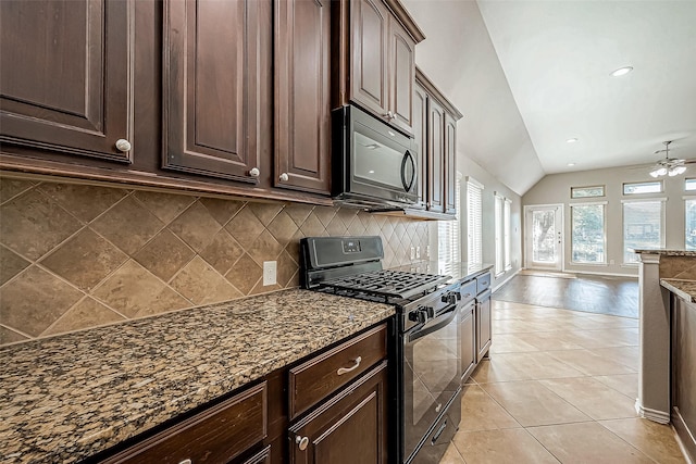 kitchen with dark brown cabinetry, dark stone countertops, lofted ceiling, and stainless steel range with gas stovetop