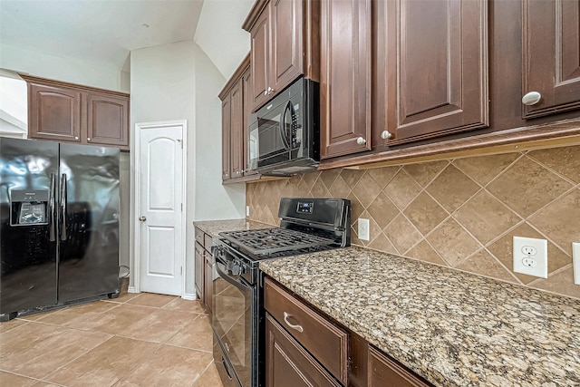 kitchen featuring black appliances, dark stone countertops, light tile patterned floors, and backsplash