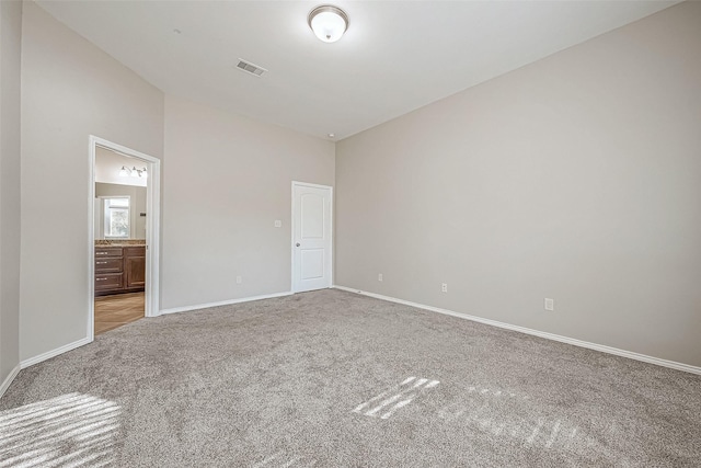 unfurnished bedroom featuring connected bathroom and light colored carpet