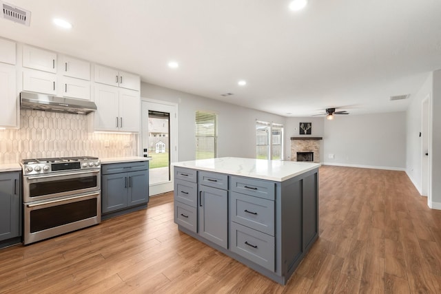 kitchen with white cabinets, hardwood / wood-style flooring, range with two ovens, and ceiling fan