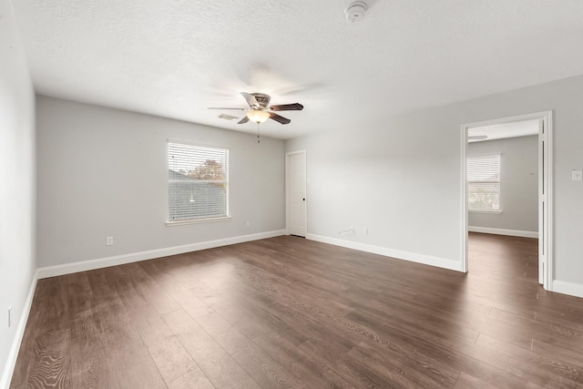 unfurnished room with plenty of natural light, dark hardwood / wood-style floors, a textured ceiling, and ceiling fan