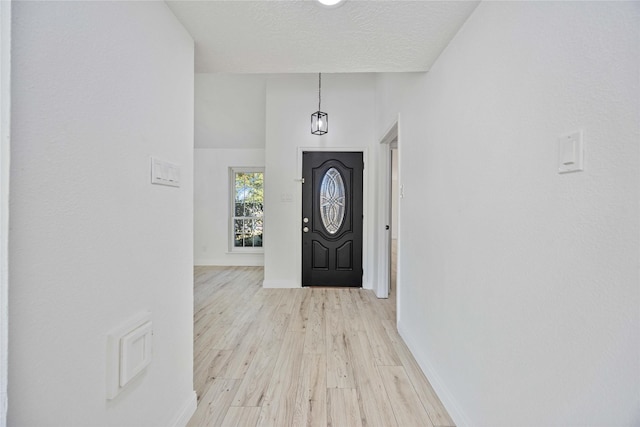 entrance foyer with a towering ceiling, light hardwood / wood-style floors, and a textured ceiling