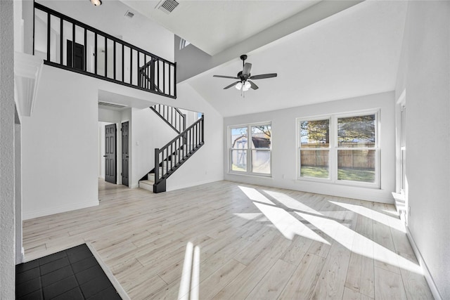 unfurnished living room with beam ceiling, ceiling fan, light hardwood / wood-style flooring, and high vaulted ceiling