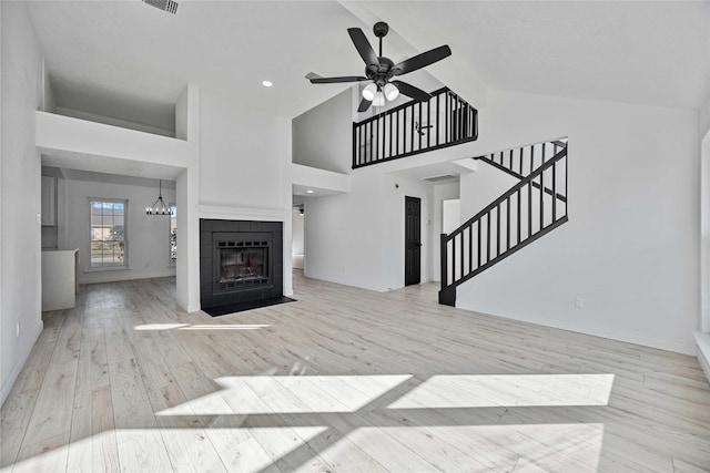 living room featuring ceiling fan, a tile fireplace, high vaulted ceiling, and light hardwood / wood-style flooring