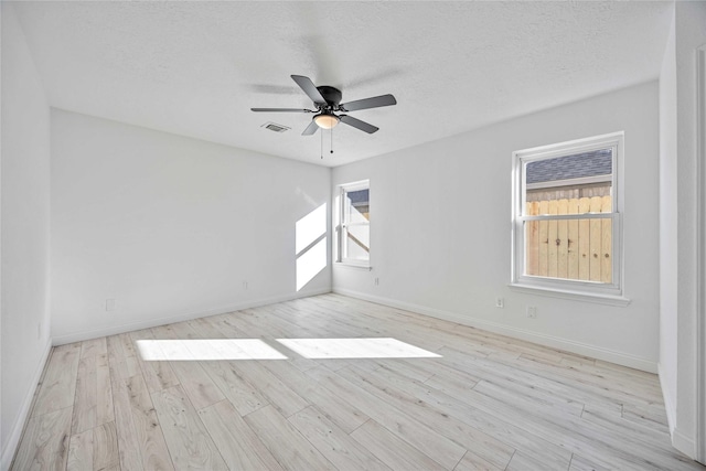 empty room with ceiling fan, light hardwood / wood-style floors, and a textured ceiling