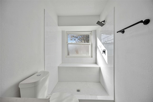 bathroom with a tile shower and toilet