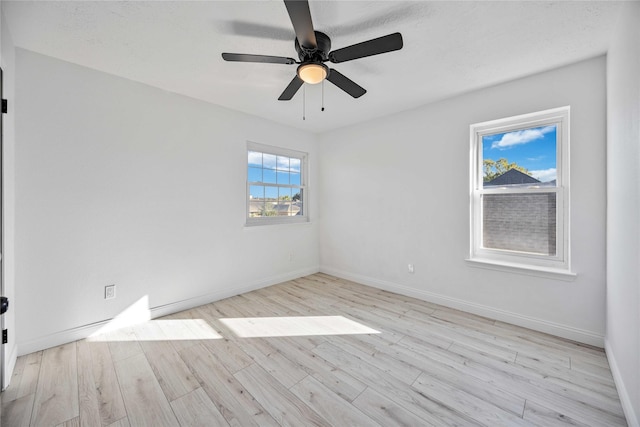 spare room with ceiling fan, light wood-type flooring, and a wealth of natural light