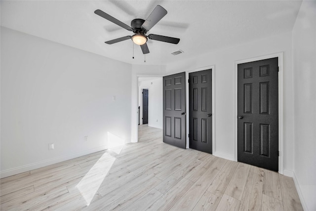 unfurnished bedroom featuring multiple closets, ceiling fan, and light wood-type flooring