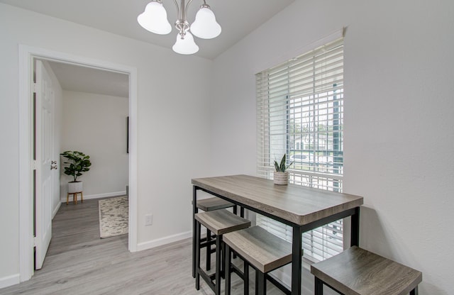 dining area with light wood-type flooring and a notable chandelier