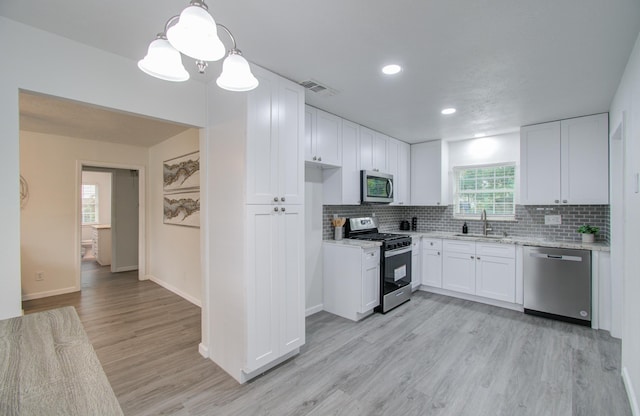 kitchen featuring sink, white cabinetry, stainless steel appliances, and a wealth of natural light