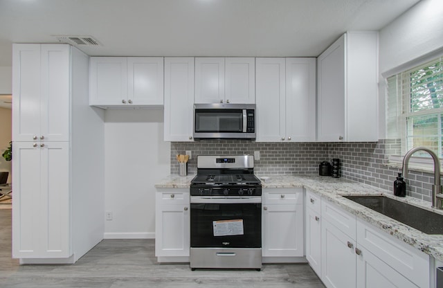 kitchen with white cabinetry, sink, light hardwood / wood-style flooring, and appliances with stainless steel finishes