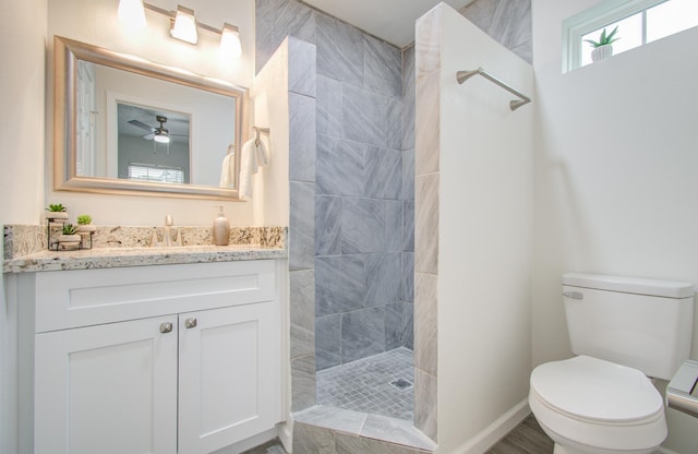 bathroom featuring tiled shower, ceiling fan, vanity, and toilet