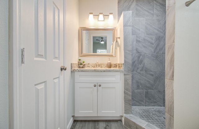 bathroom with hardwood / wood-style floors, vanity, and tiled shower