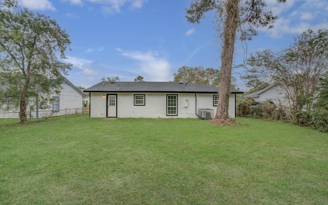 rear view of property featuring central AC unit and a yard